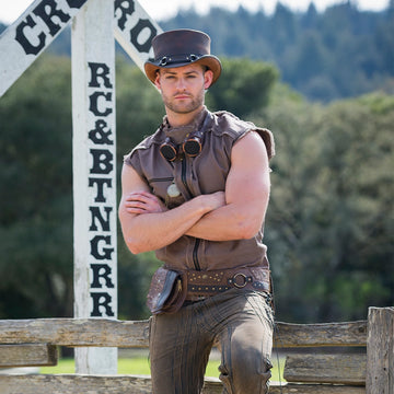 Man in a cowboy outfit standing in front of a wooden fence with a blurred background