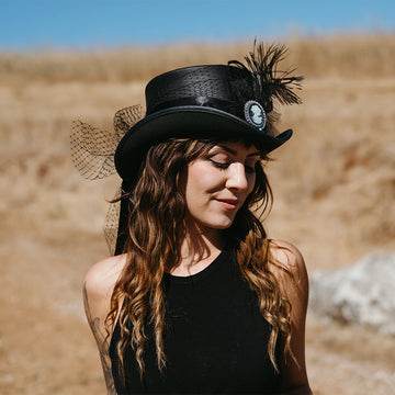 Woman wearing a black hat with feathers in a desert-like setting