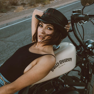 Woman sitting on a motorcycle with 'Harley-Davidson' branding, wearing a helmet.