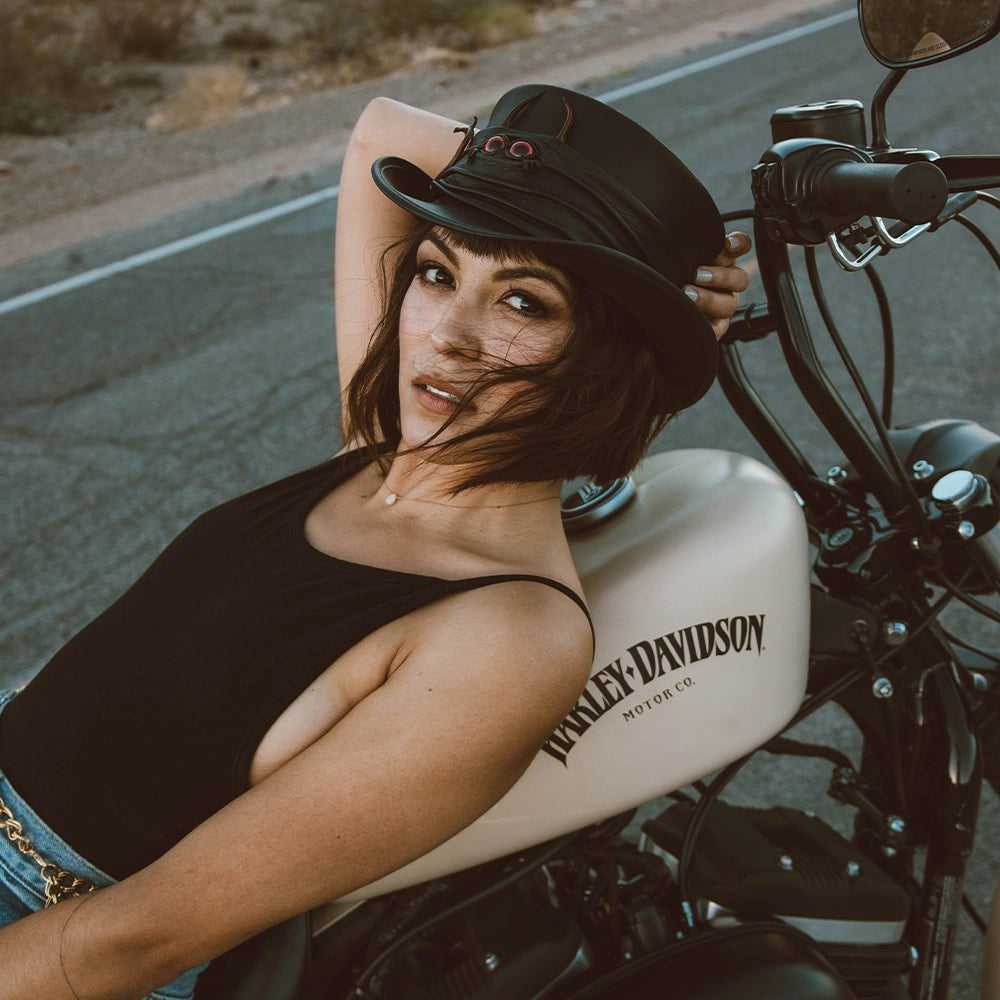 Woman sitting on a motorcycle with 'Harley-Davidson' branding, wearing a helmet.