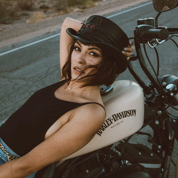 Woman sitting on a motorcycle with 'Harley-Davidson' branding, wearing a helmet.