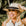 Woman wearing a straw hat with a black band, smiling outdoors.