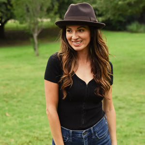Woman wearing a black hat and black top in a park