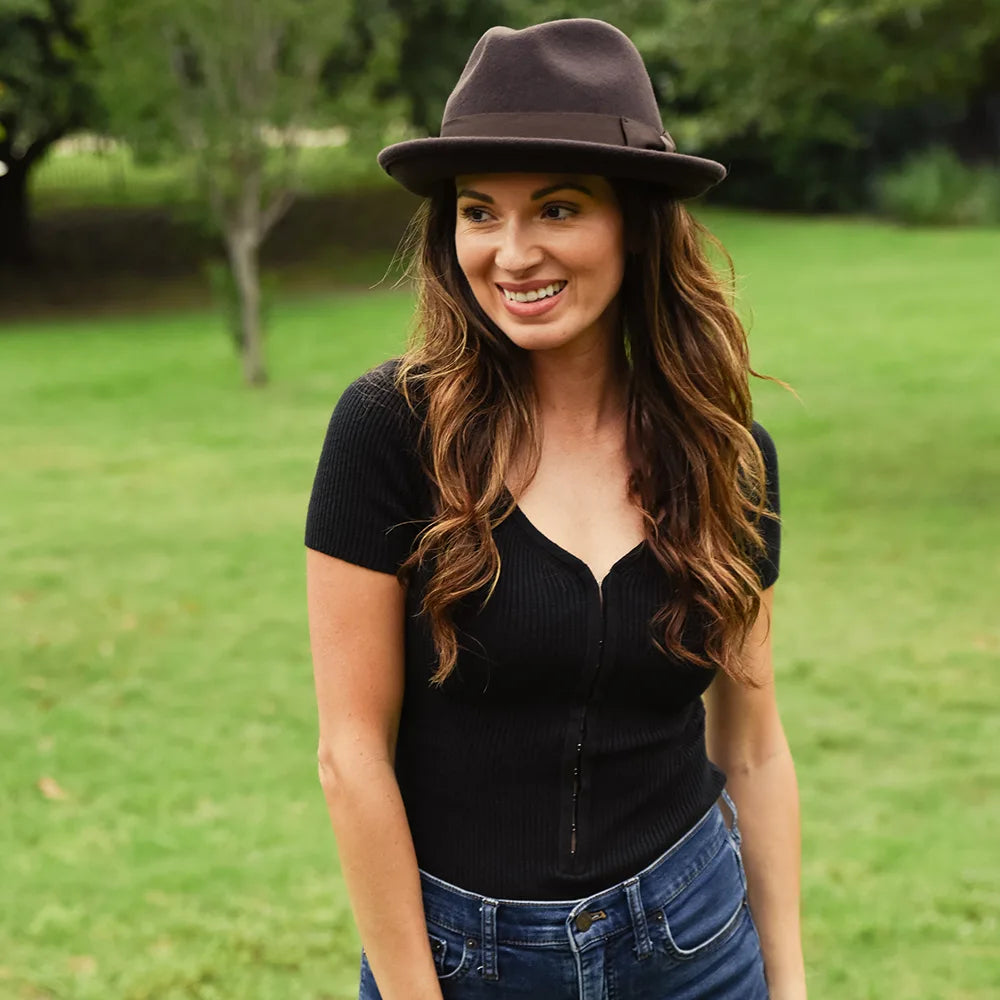 Woman wearing a black hat and black top in a park