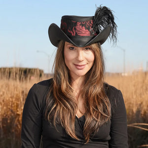 Woman wearing a black cowboy hat with red interior and feather in a field.