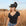 Woman wearing a black cowboy hat with feathers in an outdoor setting