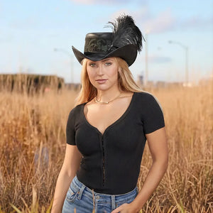 Woman wearing a black cowboy hat with feathers in an outdoor setting