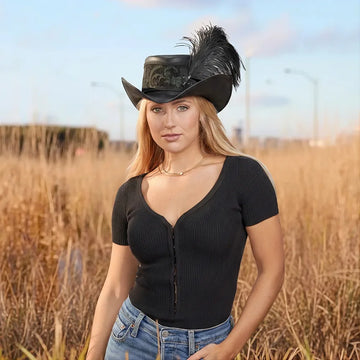 Woman wearing a black cowboy hat with feathers in an outdoor setting