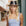 Woman wearing a black and brown hat and light blue dress on a street.