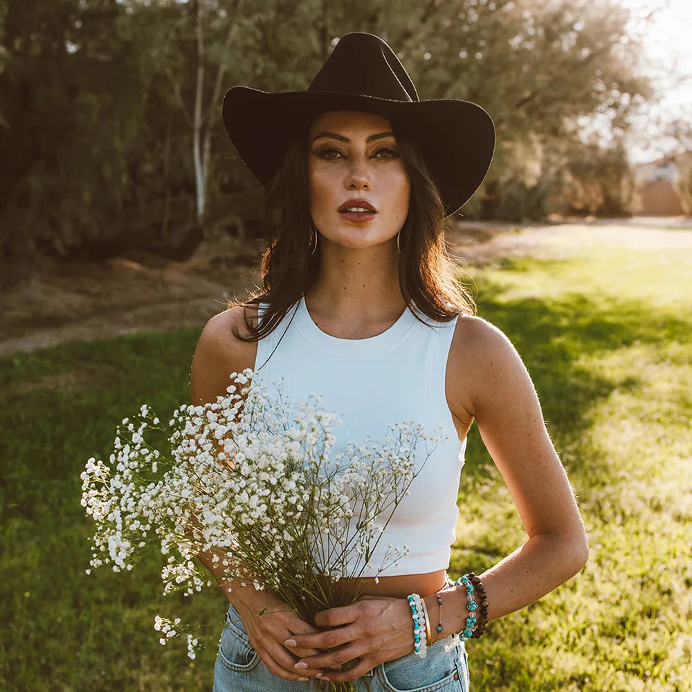 Woman holding a bouquet of white flowers in a grassy field