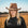 Woman wearing a brown cowboy hat in a field with a clear sky