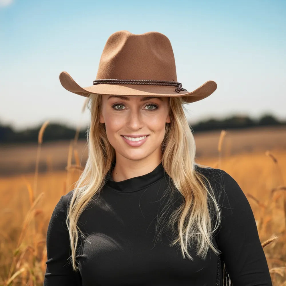 Woman wearing a brown cowboy hat in a field with a clear sky