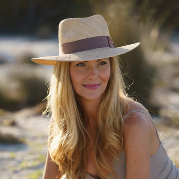 Woman wearing a wide-brimmed hat with a brown band outdoors