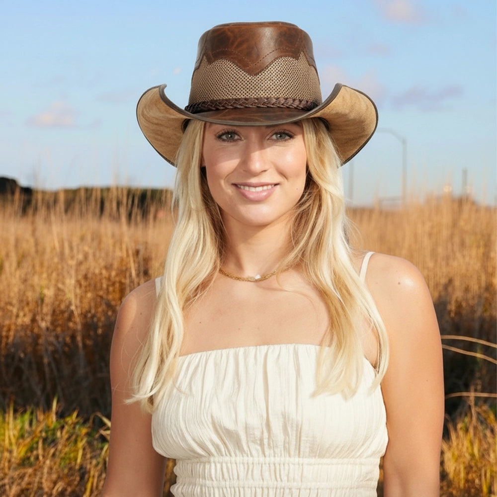 Woman wearing a cowboy hat in a field with a clear sky
