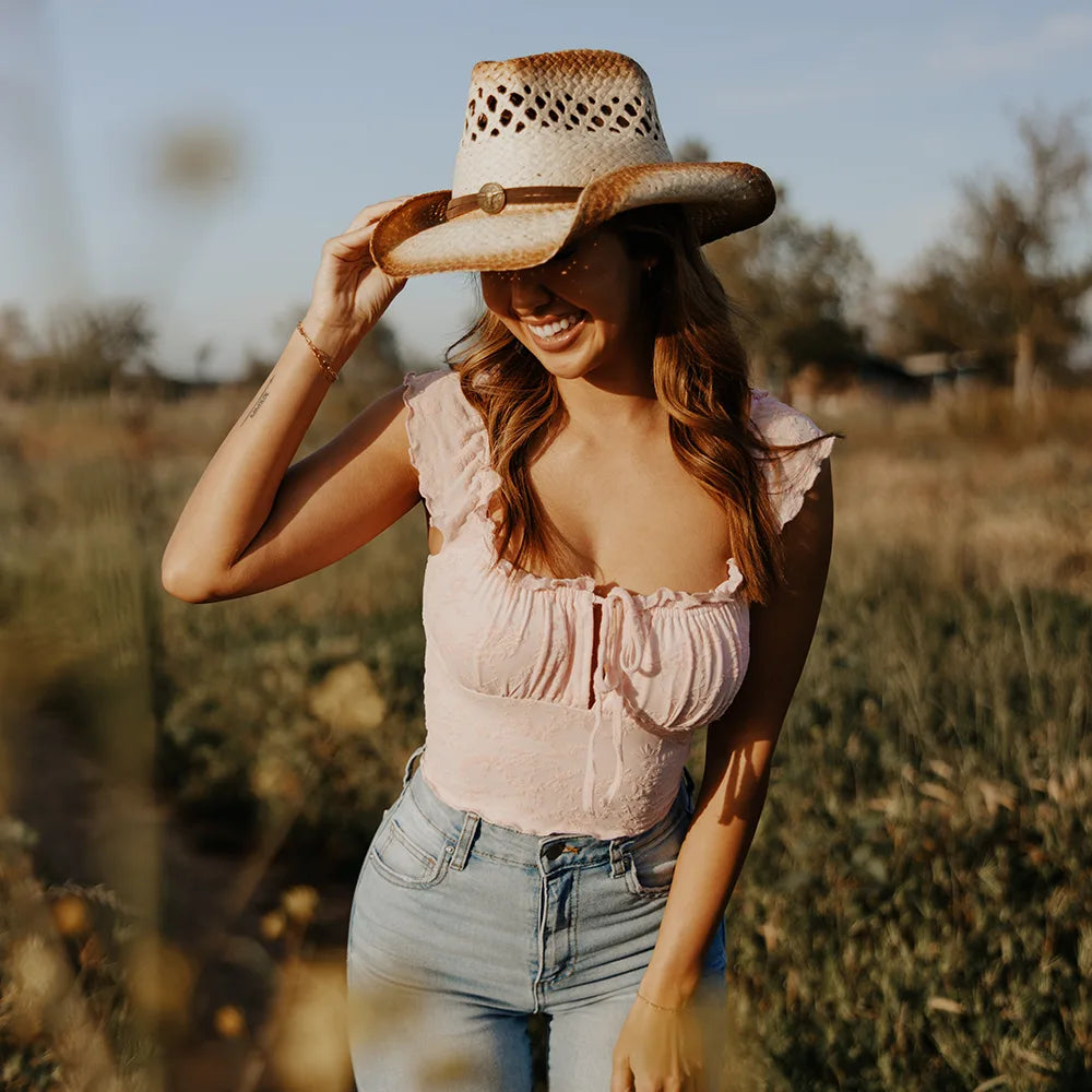 Woman wearing a straw hat and pink top in a field