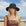 Woman wearing a black sun hat on a beach with a clear sky.