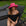 Woman wearing a black swimsuit and pink hat sitting on a lounge chair outdoors.