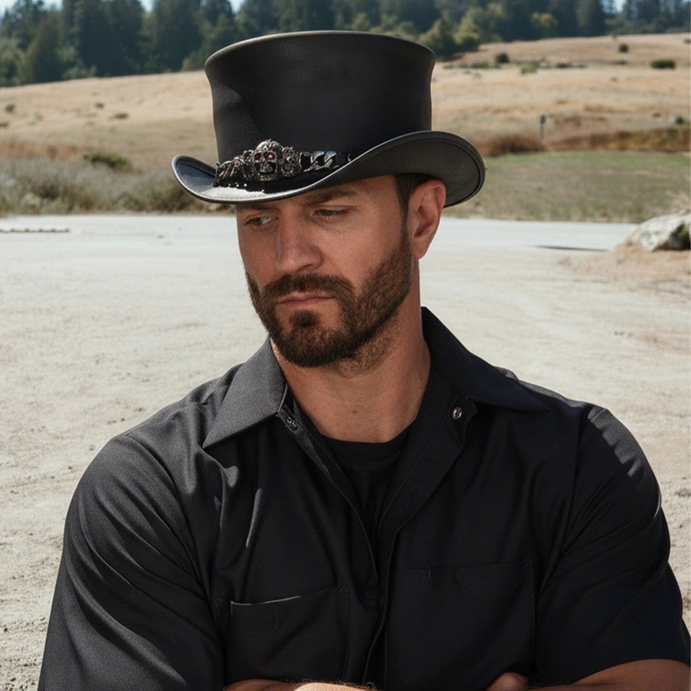 Man wearing a black cowboy hat with a decorative band in an open field.