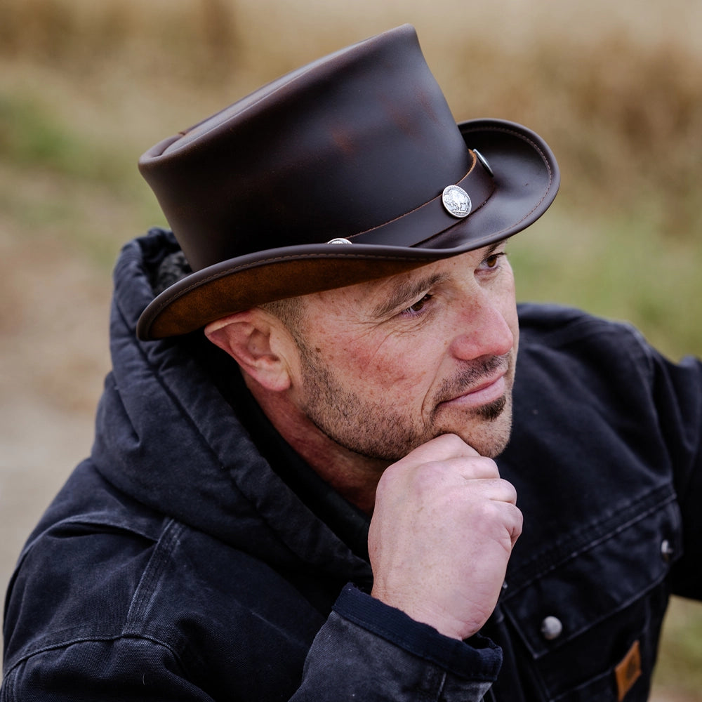 Man wearing a black top hat and dark coat outdoors