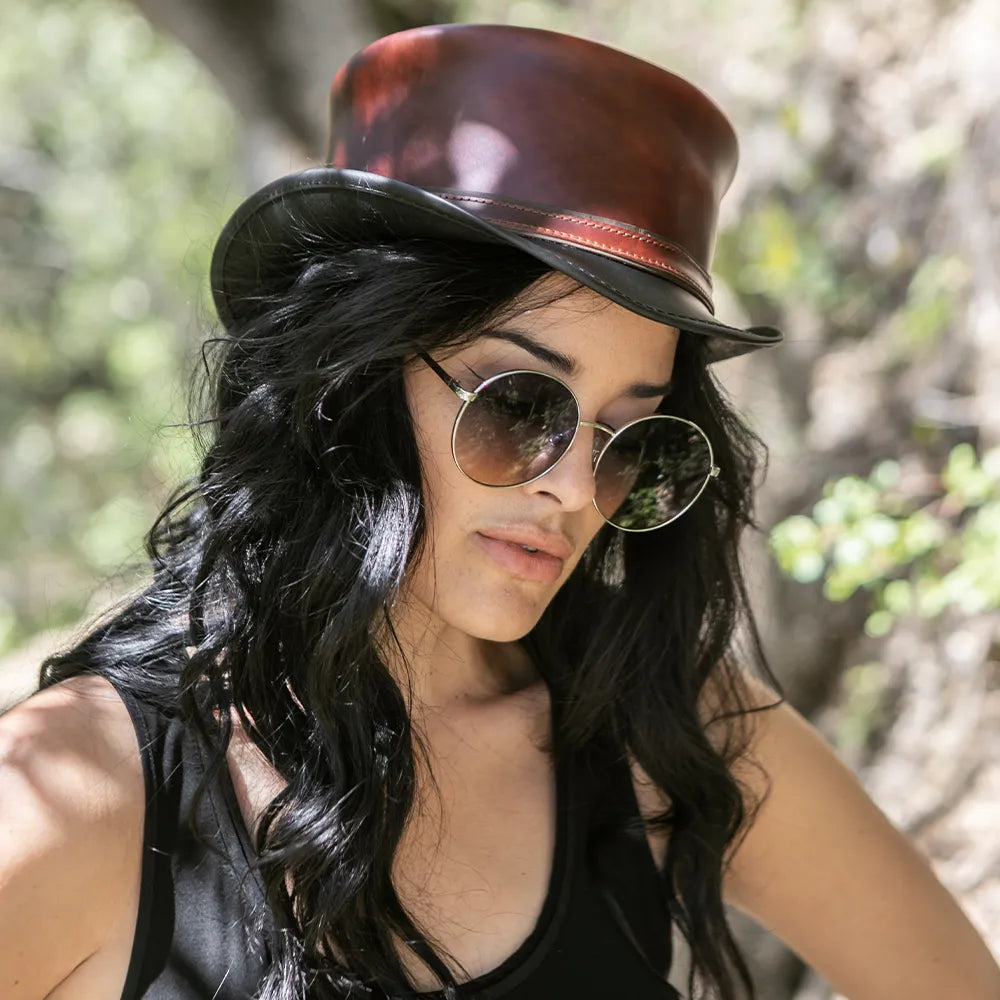 Woman wearing a brown leather hat and round sunglasses outdoors