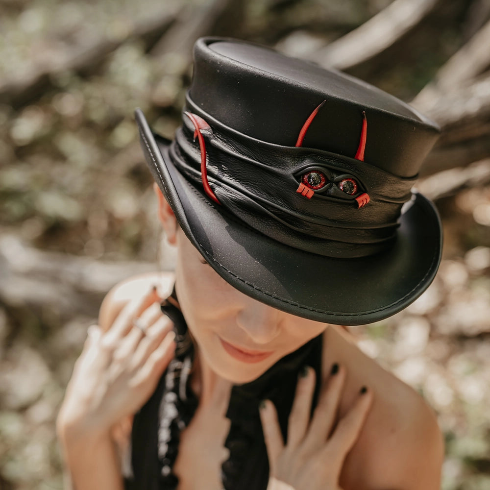 Person wearing a black top hat with red accents against a blurred natural background