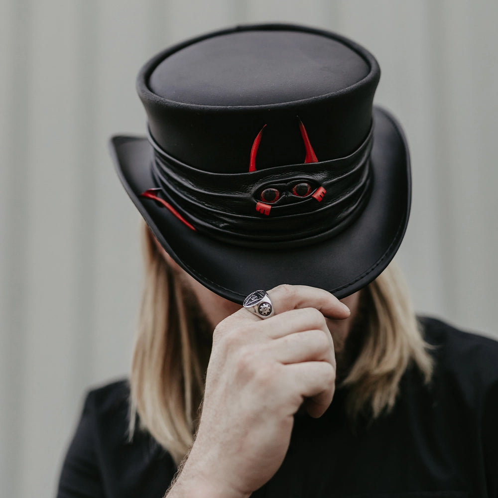Person wearing a black top hat with red accents, holding it with one hand.