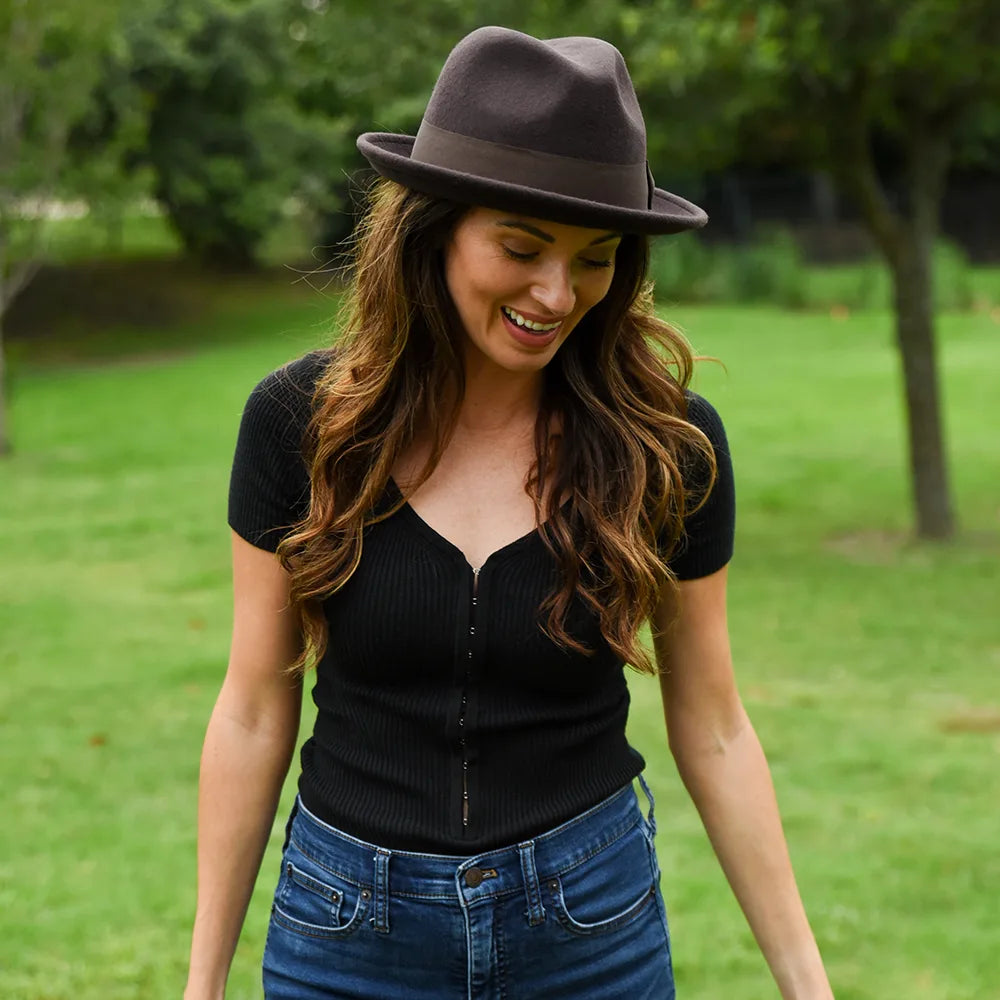 Woman wearing a black top and brown hat in a park