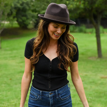 Woman wearing a black top and brown hat in a park