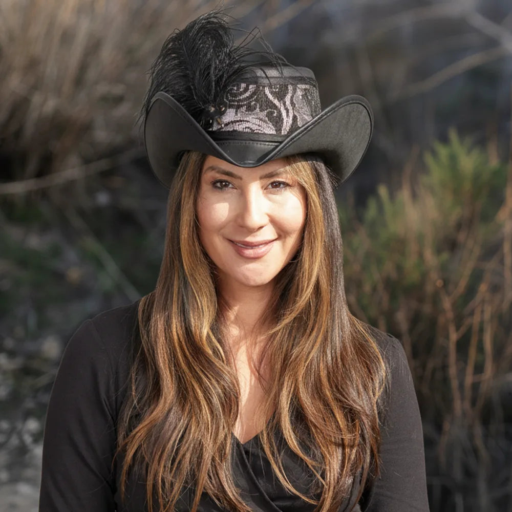 Woman wearing a black cowboy hat with feathers against a natural background