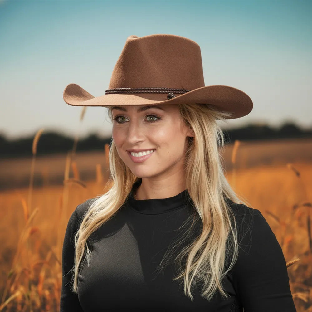 Woman wearing a brown cowboy hat in a field with a blurred background