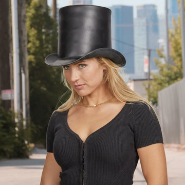 Woman wearing a black top hat and black dress in an urban setting