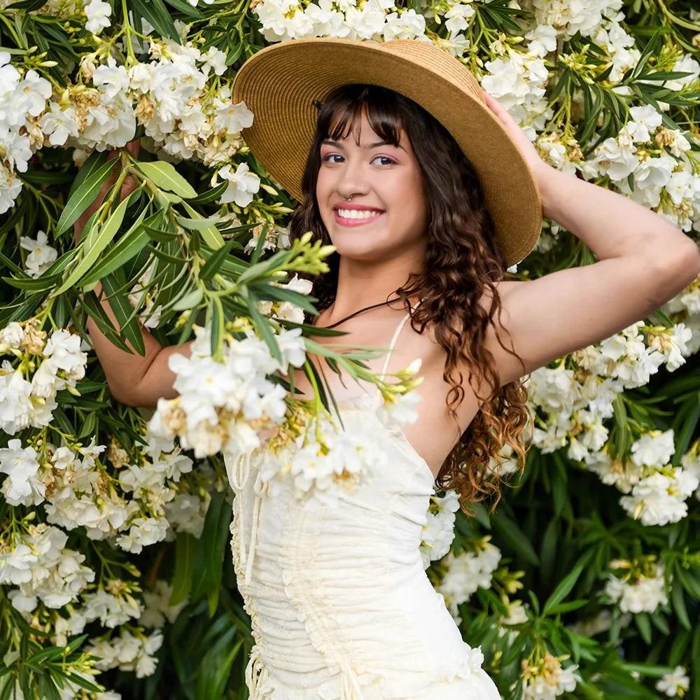 Woman in a straw hat and white dress standing among white flowers