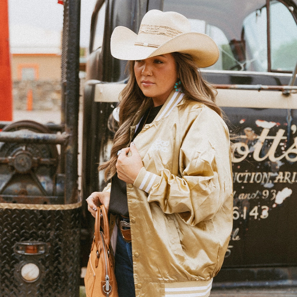 Woman wearing a beige cowboy hat and jacket standing in front of a vintage truck.