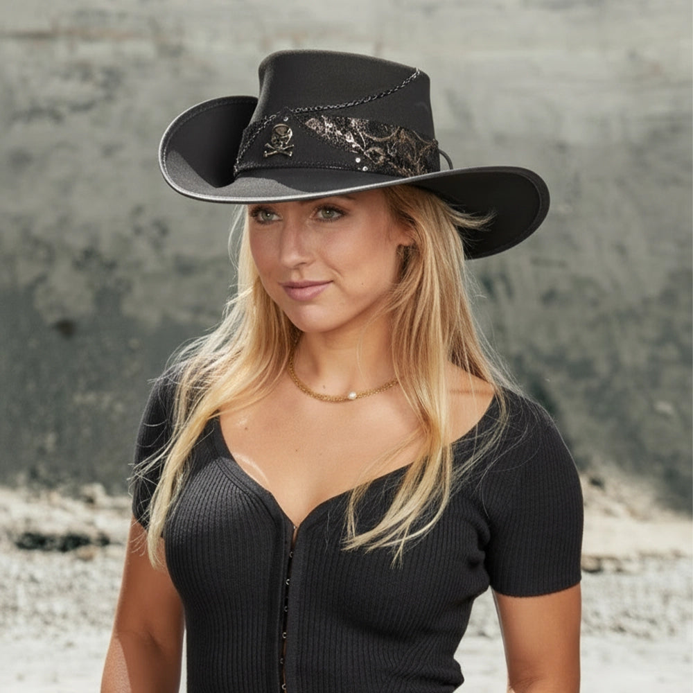 Woman wearing a black cowboy hat with decorative elements against a neutral background
