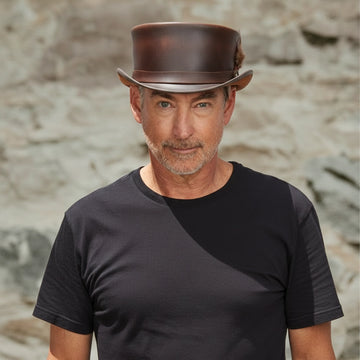 Man wearing a brown leather hat against a rocky background