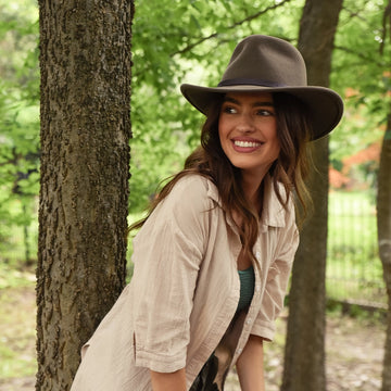 Woman wearing a brown hat in a forest setting
