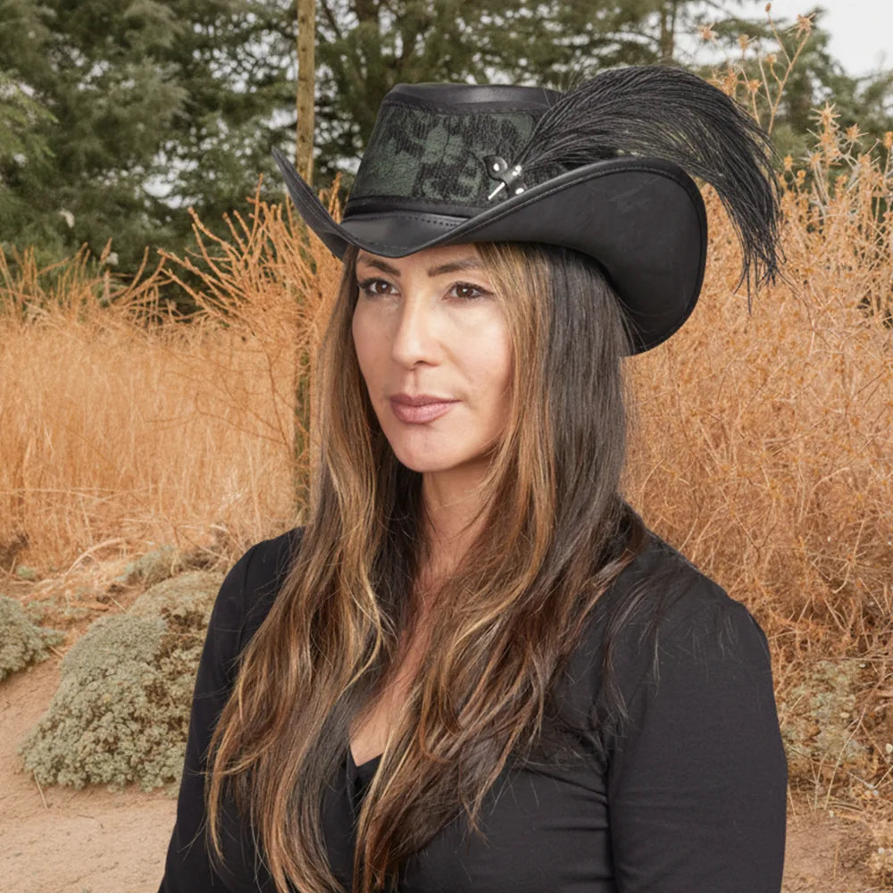 Woman wearing a black cowboy hat with a feather in an outdoor setting