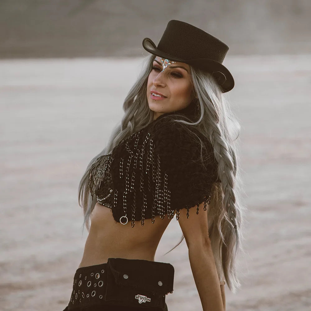 Woman wearing a black cowboy hat and embellished top with a blurred background