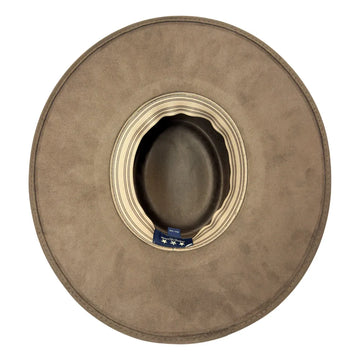 A top-down view of a wide-brimmed cowboy hat in a taupe brown suede-like finish, featuring a cream striped inner band and a small blue brand tag.
