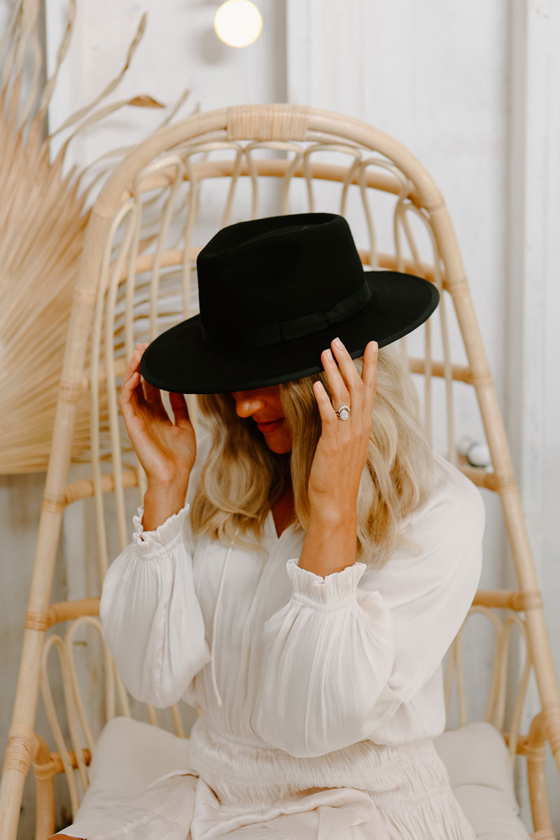 A woman in a white dress wearing a black felt hat