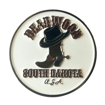 A circular enamel pin featuring a black cowboy hat and boot with a spurs detail on a white background, with the text 'DEADWOOD SOUTH DAKOTA U.S.