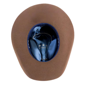 A brown cowboy hat viewed from above, showing a dark blue satin interior with white embroidered stars and the text 'AMERICAN MADE IN USA' on a white background.