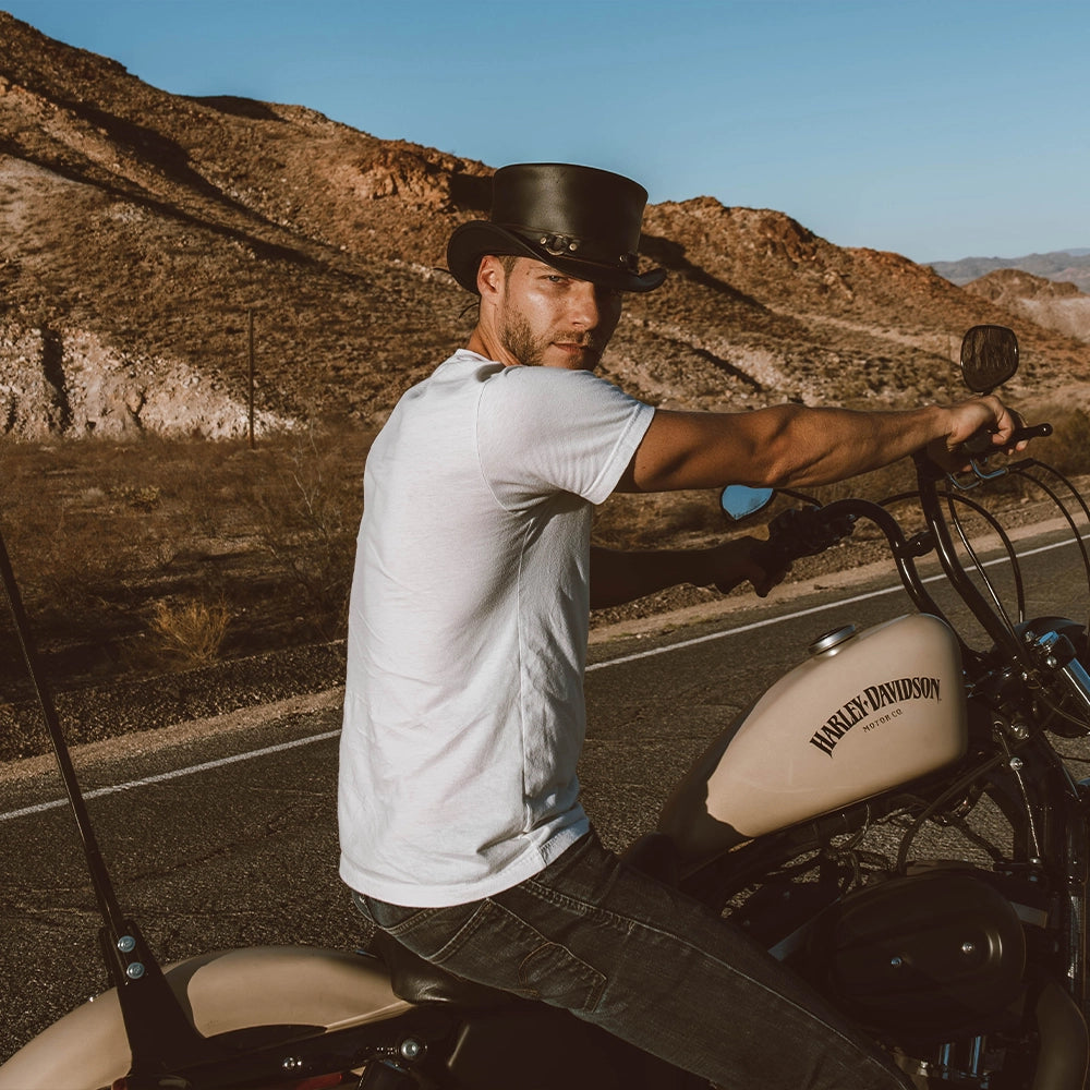Man in a cowboy hat sitting on a motorcycle in a desert setting