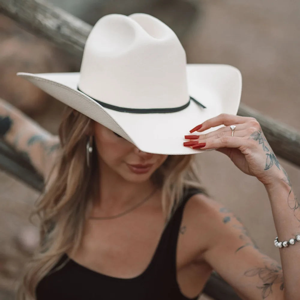 Woman wearing a white cowboy hat with a blurred background