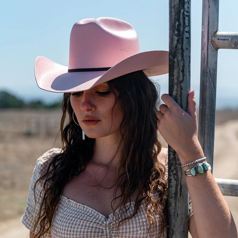 Woman wearing a pink cowboy hat in an outdoor setting