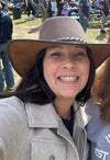 Woman wearing a cowboy hat with a blurred background of people and grass